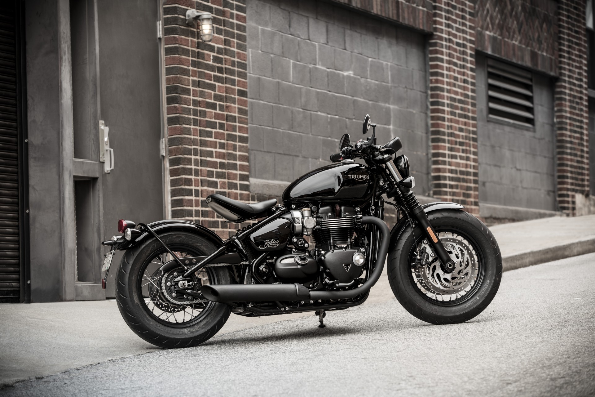 moto triumph bonneville bobber black, vista laterale ambientata