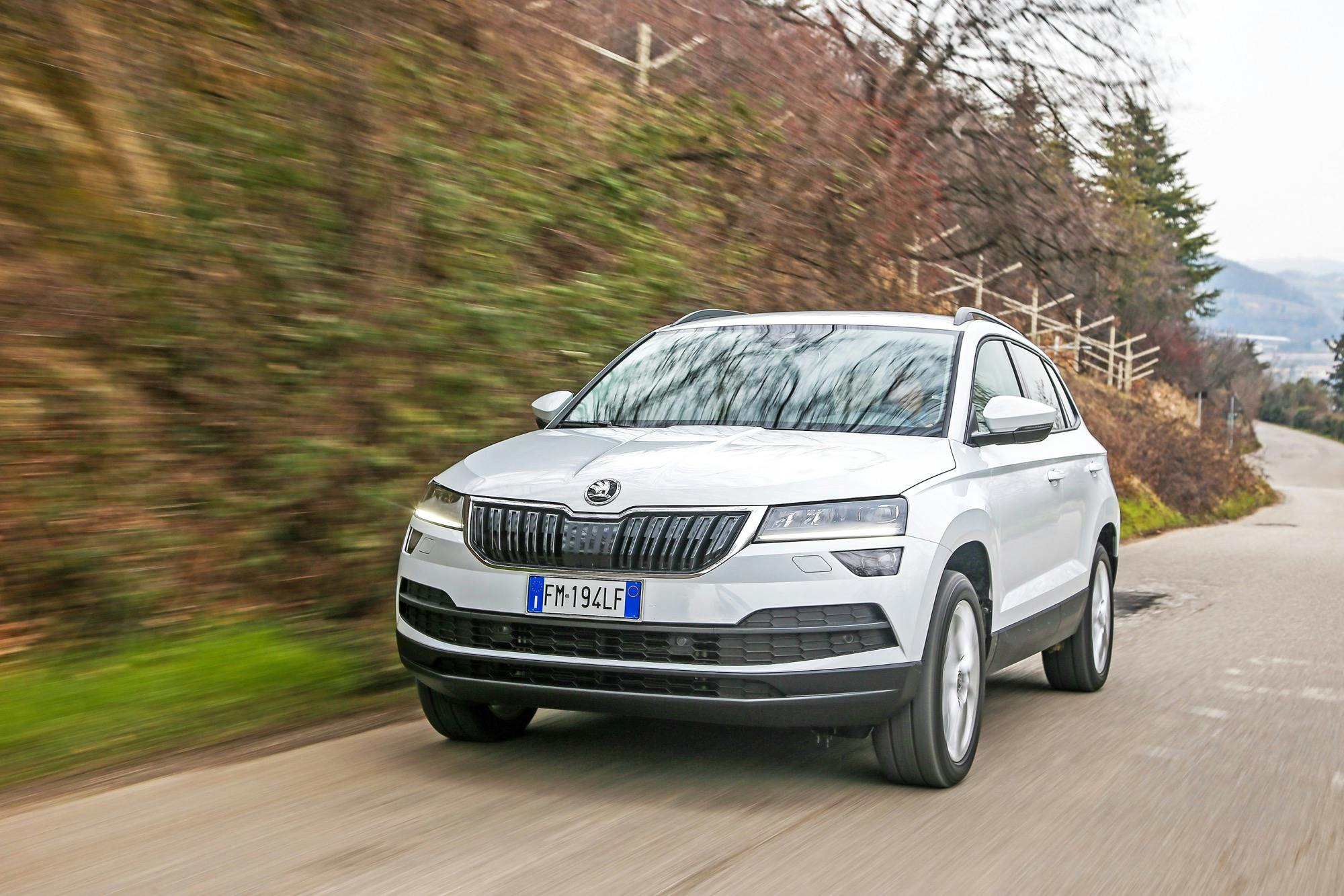 Skoda Karoq bianca in vista frontale viaggia su strada di campagna