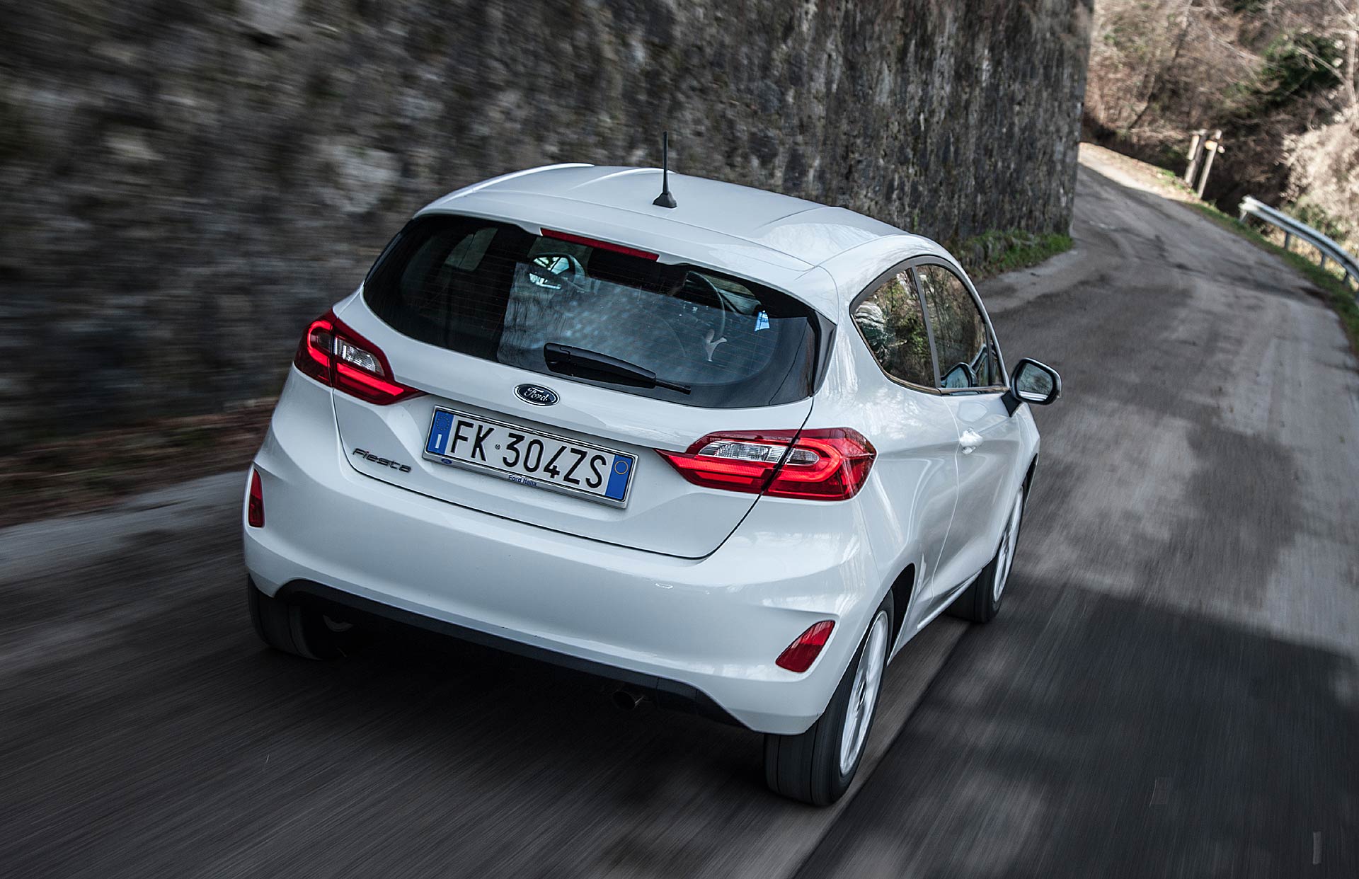 Ford Fiesta 1.5 TDCi Titanium bianca vista posteriore su stradina con muraglia a fianco