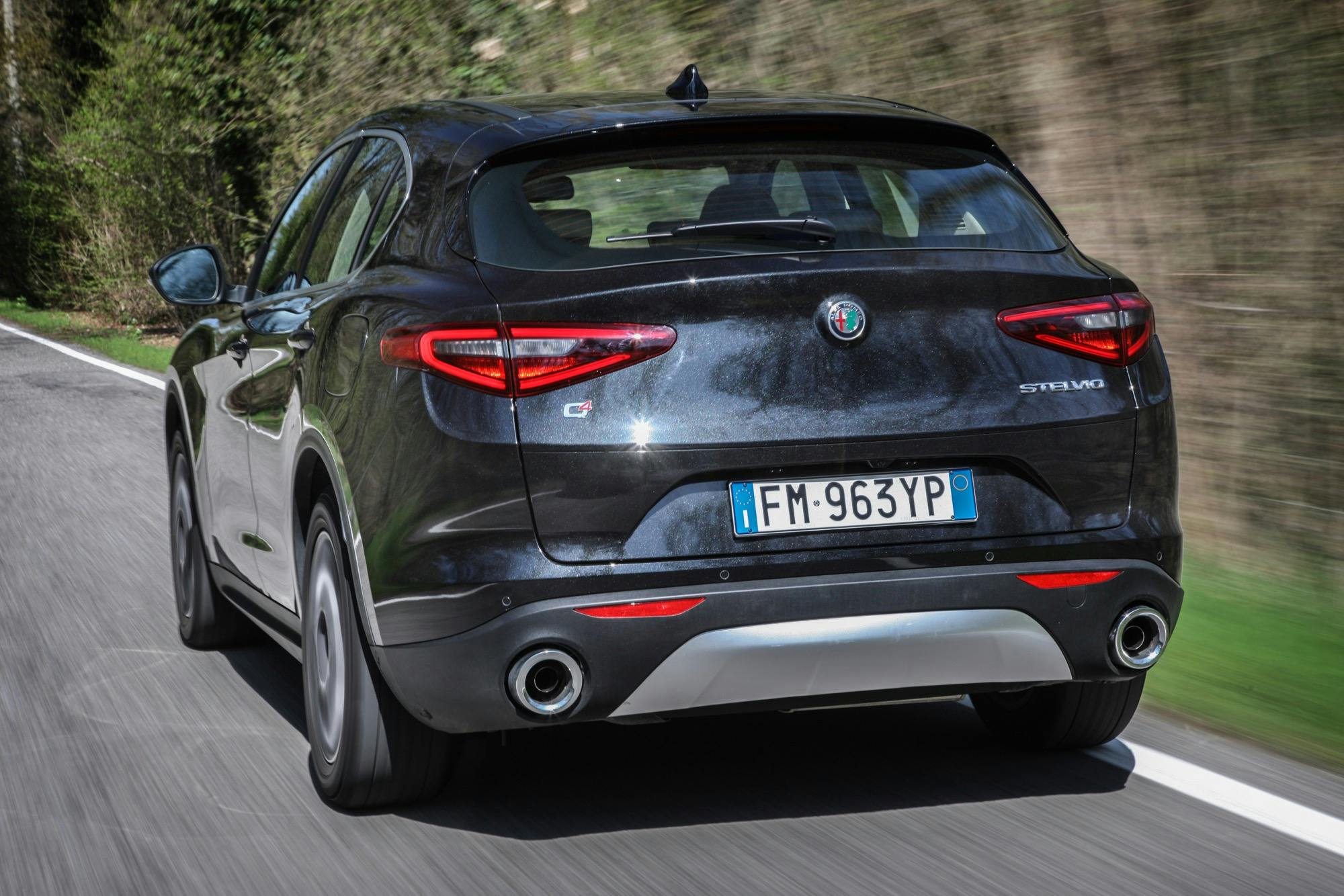 Alfa Romeo Stelvio posteriore in movimento su strada nera