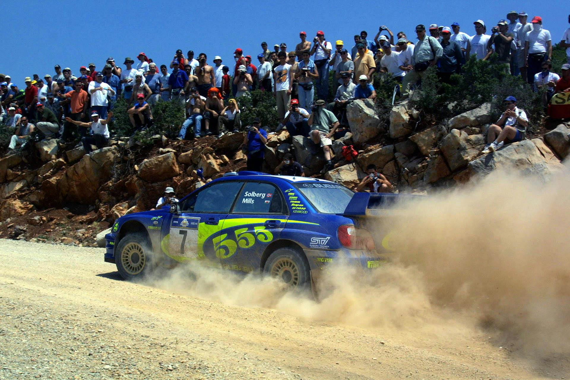 Subaru Impreza rally su sabbia laterale in movimento con spettatori blu