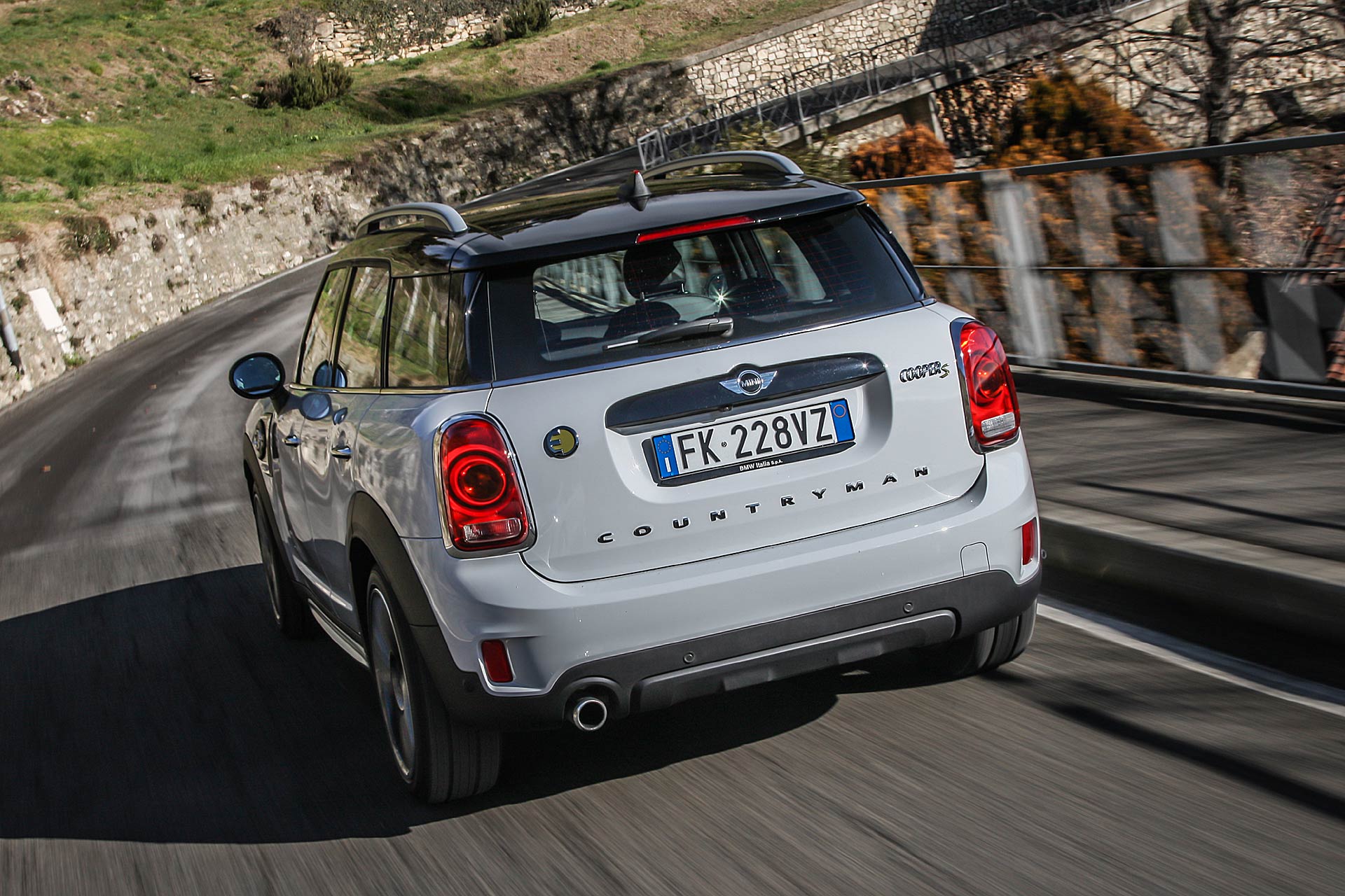 Mini Cooper Countryman SE bianca vista posteriore in curva su strada tortuosa