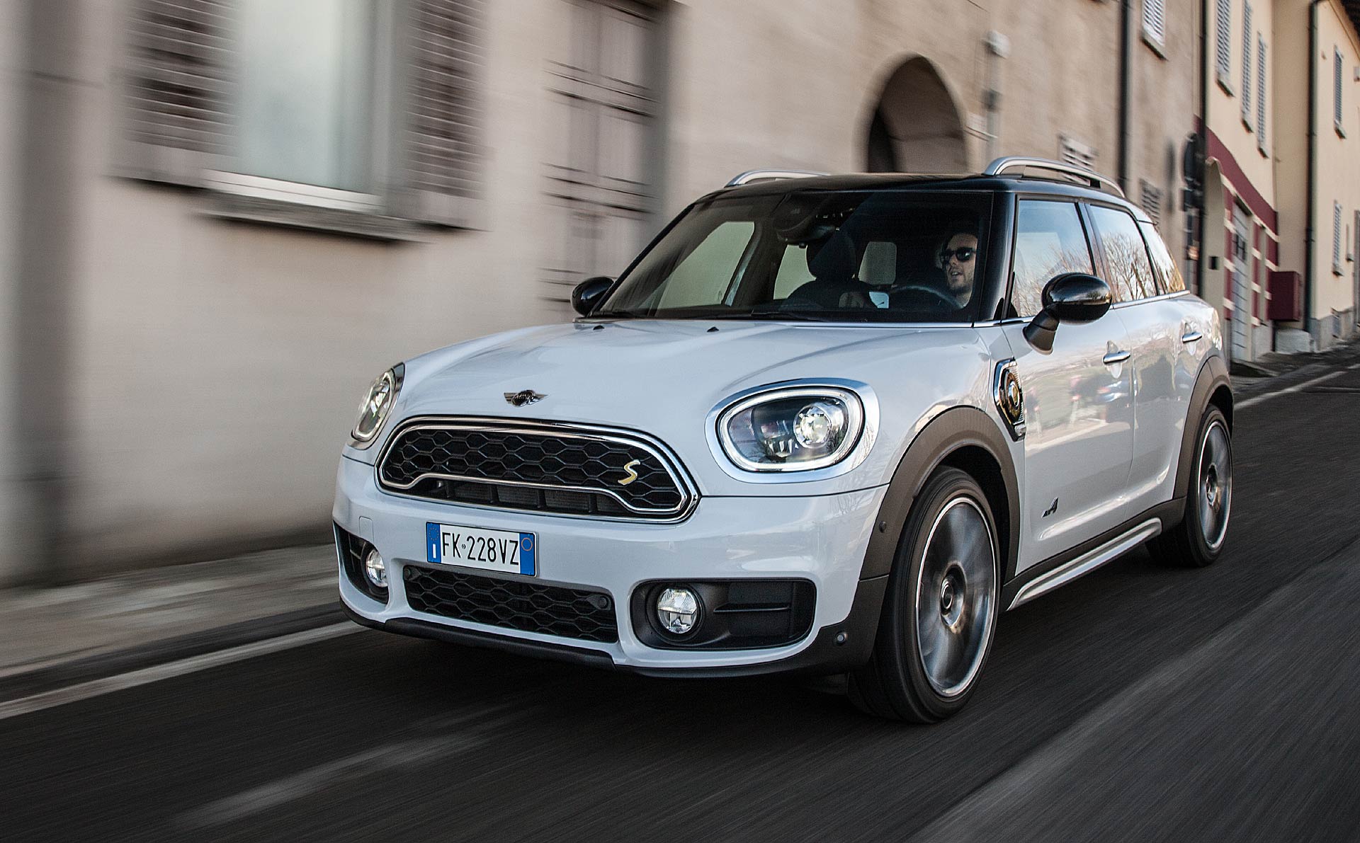 Mini Cooper Countryman SE bianca viaggia con sfondo di case rosa