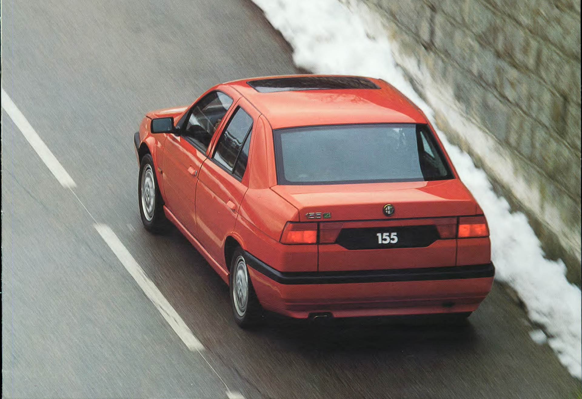 Alfa Romeo 155 Q4 rossa su strada di montagna con neve sui lati