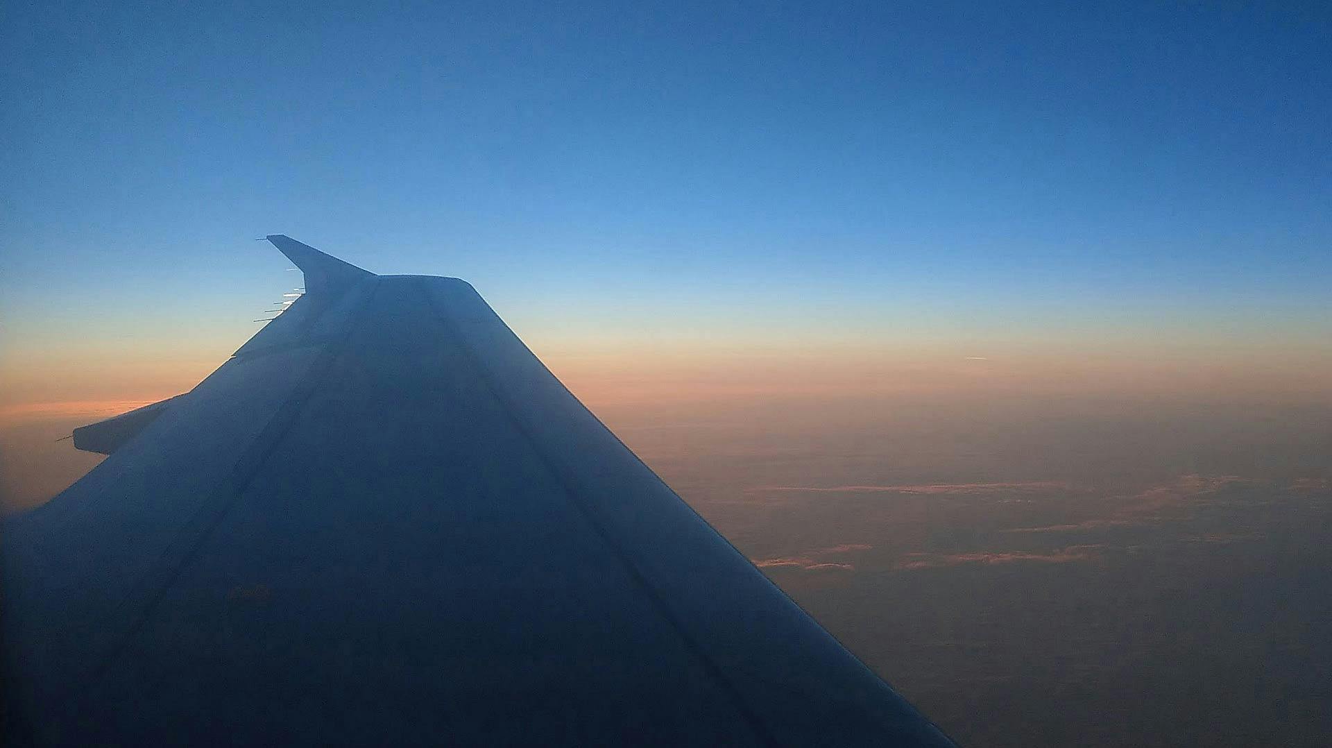 In volo si apprezza lo spettacolare cielo colorato dal tramonto rosso arancio con sfumature verdi