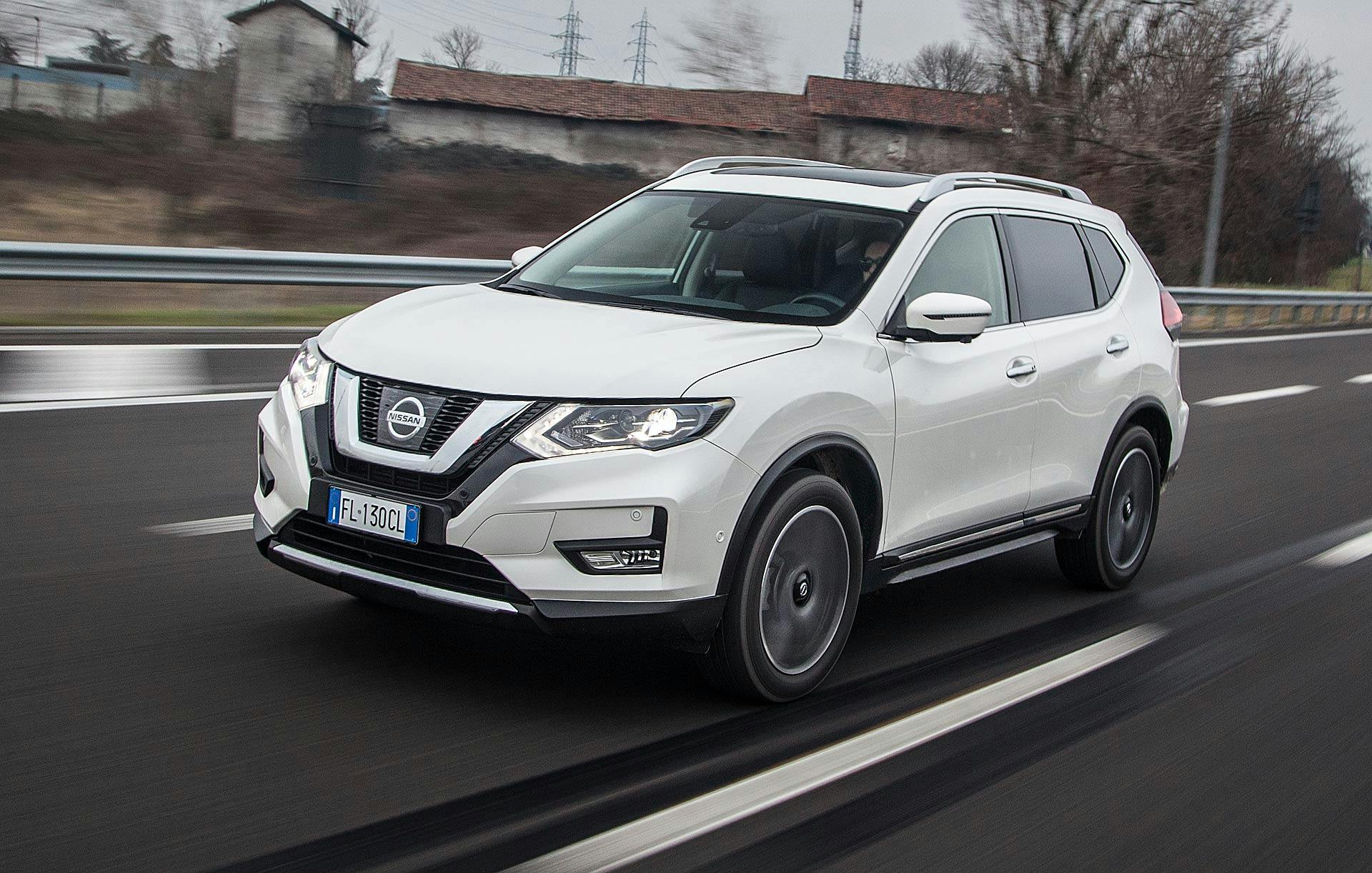Nissan X-Trail 1.6 dCi 130 CVT 2WD Tekna bianca in autostrada con dietro una cascina