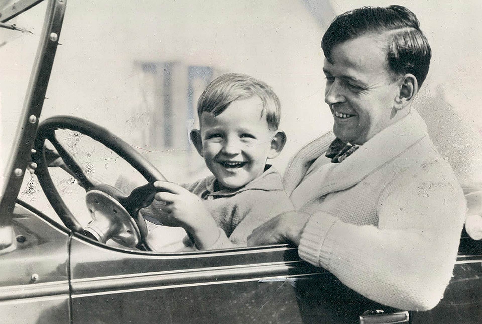 Il papà fa provare al figlio piccolo a guidare l'auto in bianco e nero