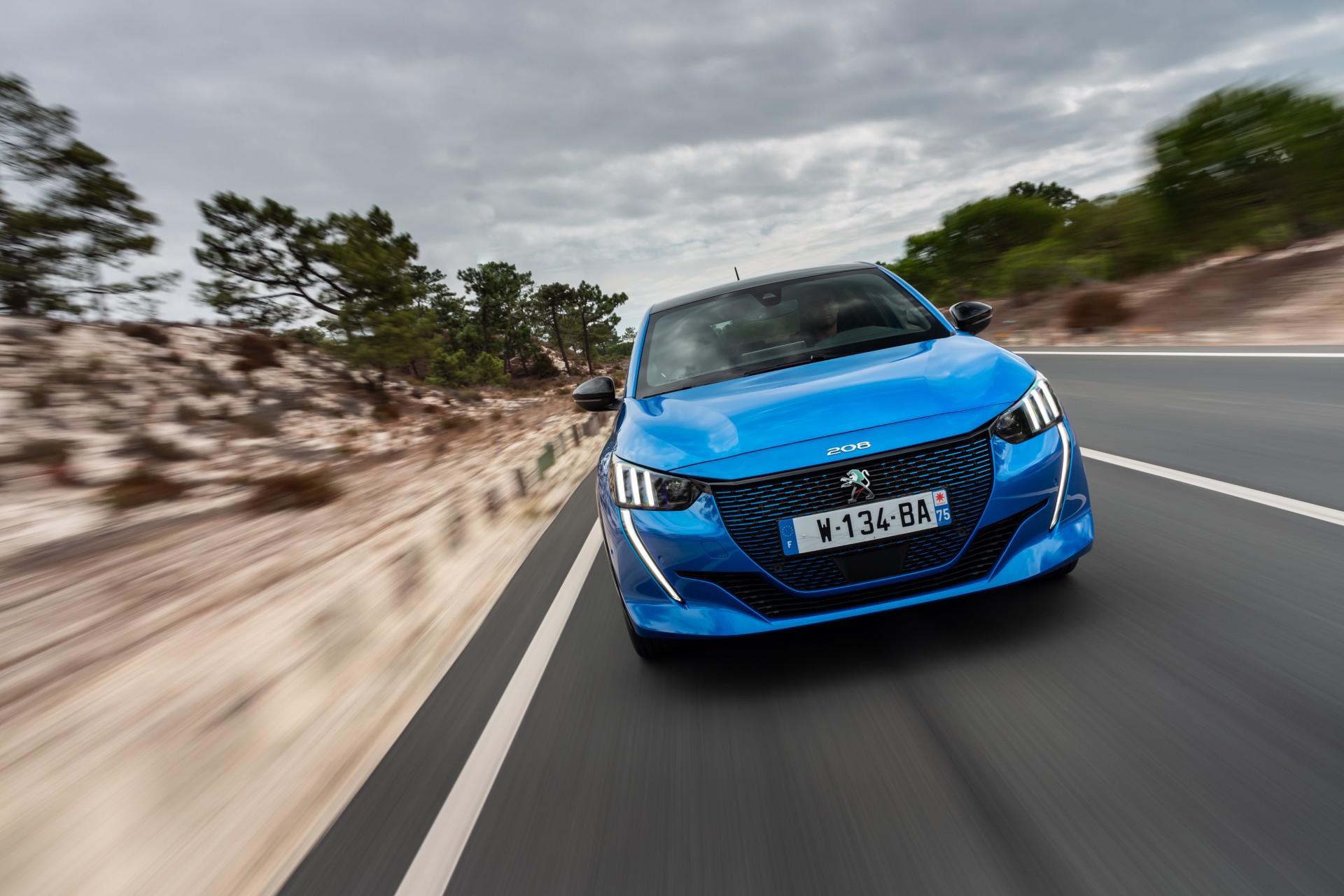 Peugeot e208 blu vista tre quarti frontale in movimento