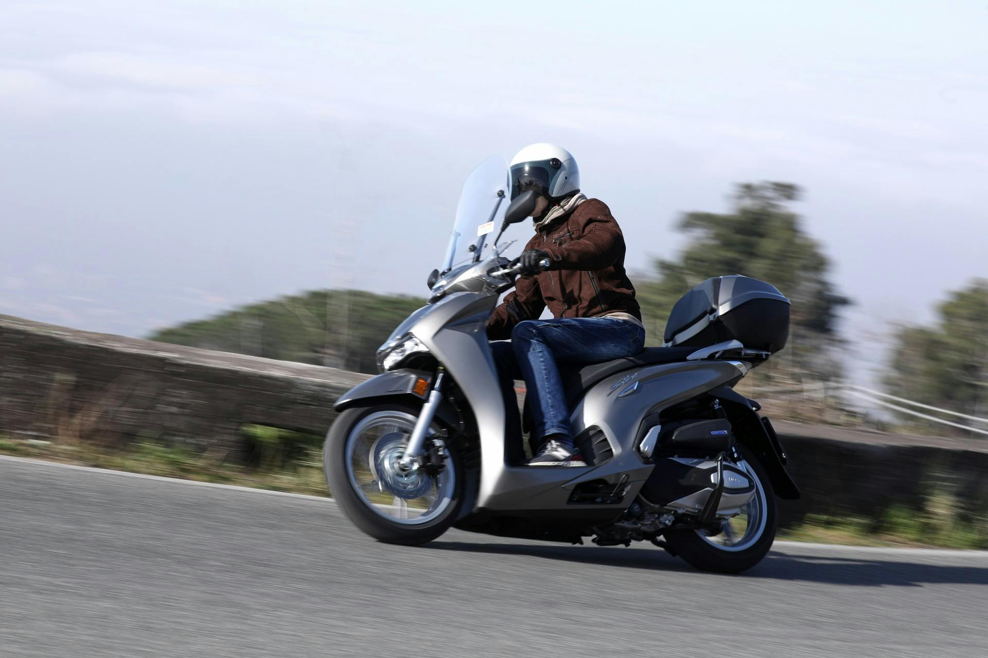 Honda SH 350 grigio in movimento su strada di montagna