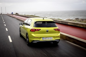 Nuova Volkswagen Golf 8 colo oro su strada con il mare sullo sfondo