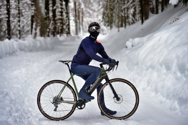 ciclista in posa con abbigliamento in vernale su strada innevata