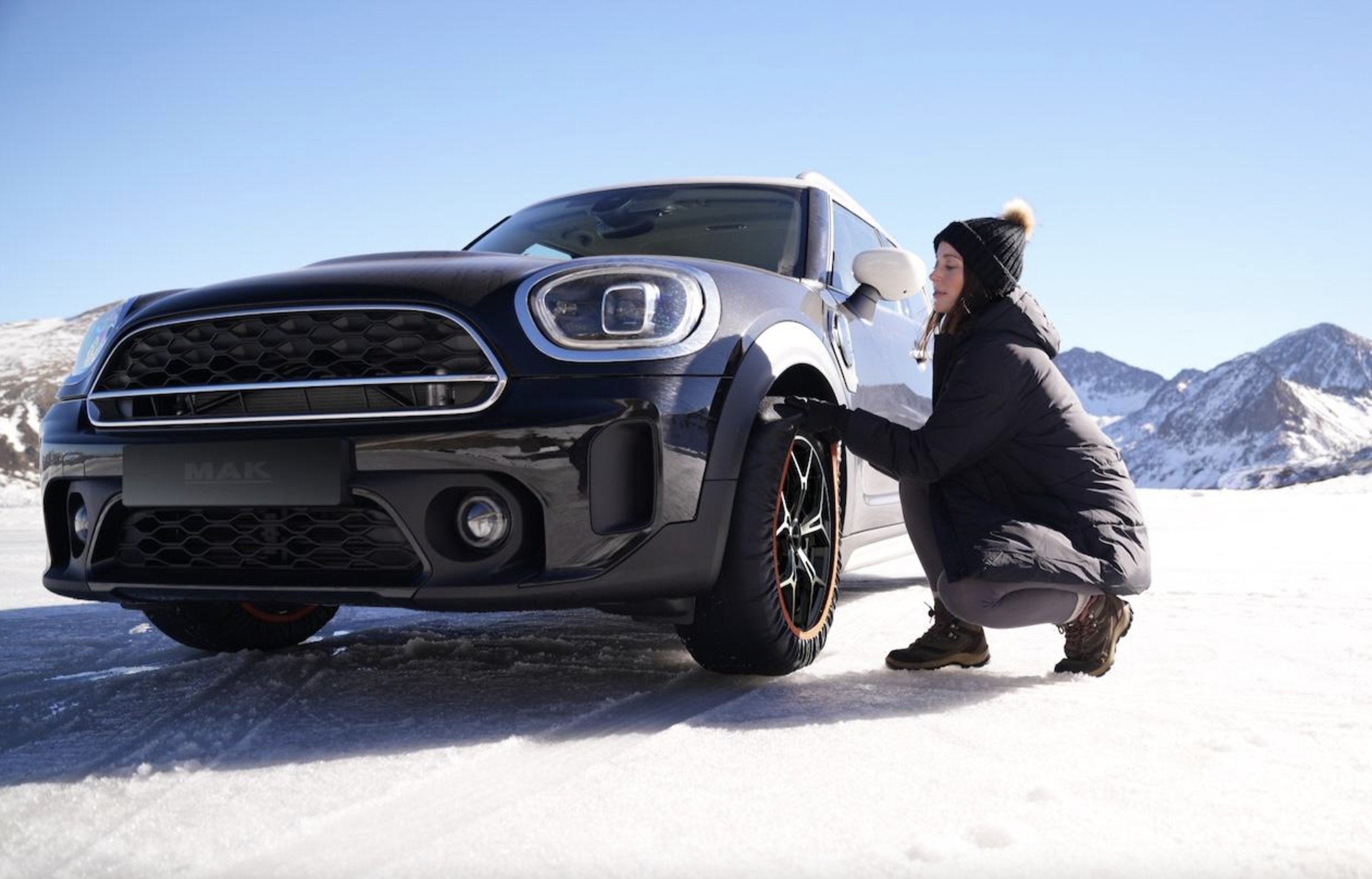 ragazza che monta le calze da neve su una auto Mini