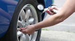 donna che controlla la pressione di un pneumatico auto con un manometro